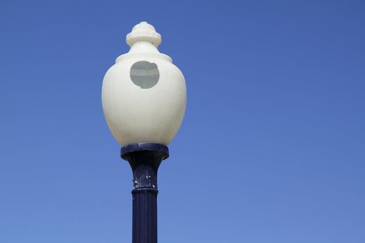 Round street lamp with a hole in the glass over blue sky