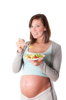 Young, positive, healthy pregnant woman eats salad. She holds a plate of mixed salad and a fork in his hand
 