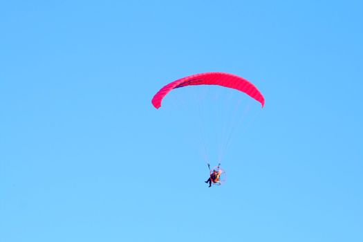 Powered paraglider flying over the blue sky