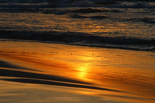 Golden sunset at the beach with reflections on coast