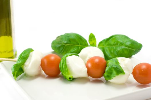 Caprese salad close-up with olive oil green basil and  pepper 