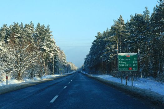 Road in winter with distances sign