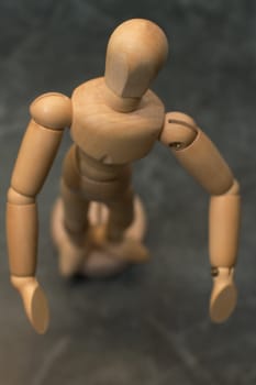 wooden toy figure looking curiously into camera, photo taken from above, shallow depth of view
