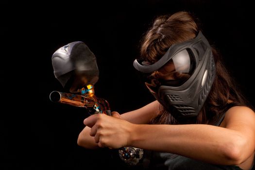 Image of a paintball player in protective helmet aiming the target