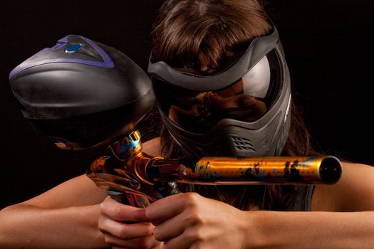 Image of a paintball player in protective helmet aiming the target