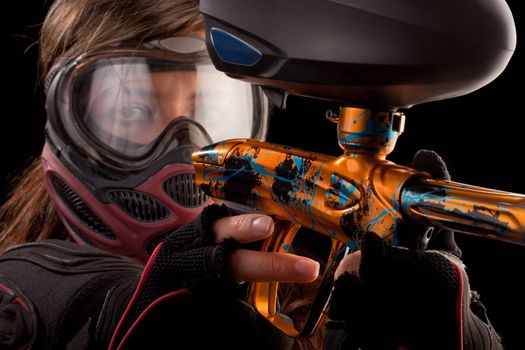 Image of a paintball player in protective helmet aiming the target