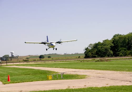 This is an medium sized twin engine plane landing on a grass landing strip.