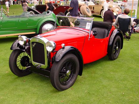 This is a red and black 1920s Austin convertible touring car taken at an antique auto show.