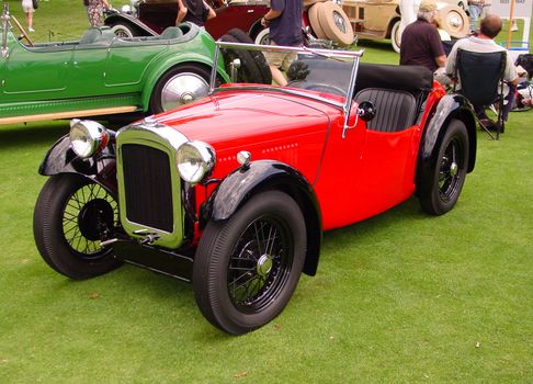 This is a red and black 1920s convertible touring car taken at an antique auto show.