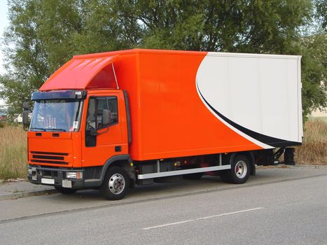 This is a picture of an orange and white, European delivery truck ready to deliver its goods.