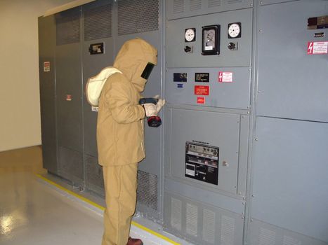 This is a picture of an electrical worker in a fire retardant flash suit used for working on high voltage equipment isolated in white
