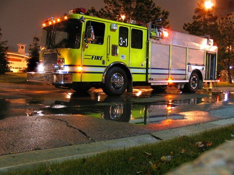 This is a fire engine, pumper truck that was hooked to a hydrant and spraying water during the evening hours.