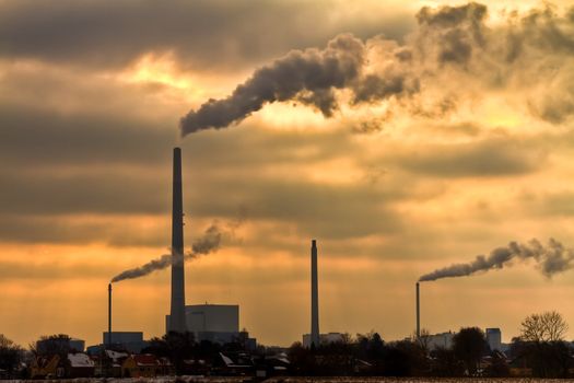 Winter scenic of power plant with a burning yellow sky behind