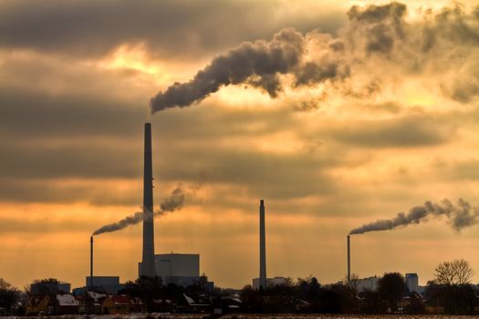 Winter scenic of power plant with a burning yellow sky behind