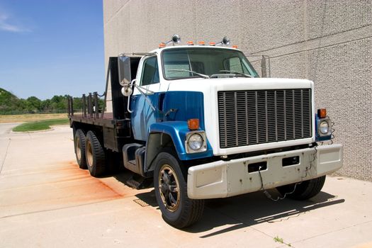 This is a mid 1980's heavy duty flatbed truck viewed from the front corner.