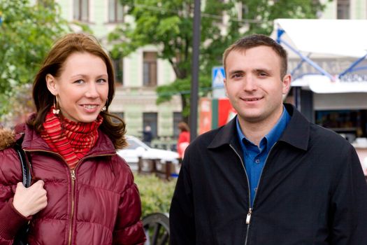 Happy young couple staring at you in spring city