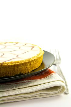 delicious looking iced bakewell tart on a black plate with a plain background