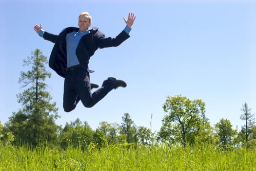 Jumping business man over meadow in sunny day