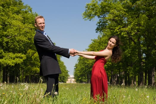 Happy young couple holding hands in summer meadow