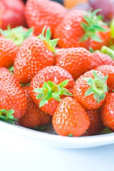 Delicious red strawberries on white plate with shallow depth of field.