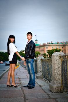 Happy young couple walking on city bridge