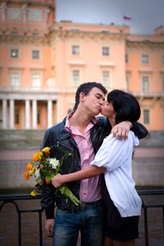 Happy young kissing couple on city bridge