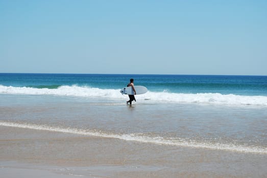 photo of a man entering ocean to practise Surf 