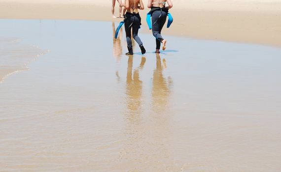 photo of young girls walking on the beach before surf