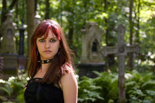 Gothic girl walking through cemetery looking at you