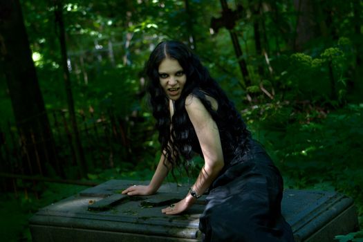 Vampire sitting on gravestone in the dark