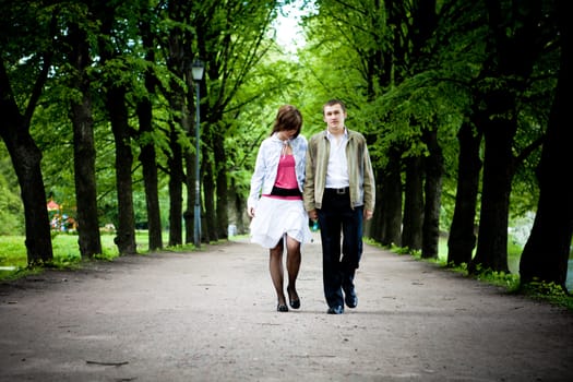 Happy young couple walking through valley in park 