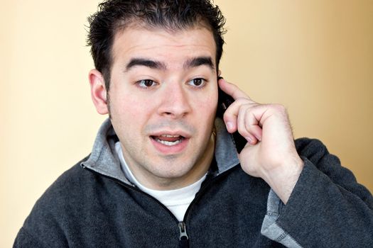 A young man talking on his cell phone with a concerned look on his face.