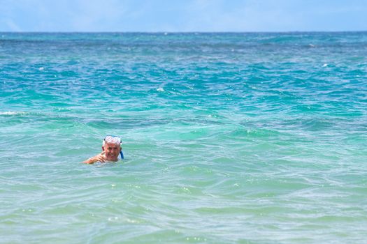 An older elderly man snorkels in tropical waters in the Caribbean off of the Puerto Rican island of Culebra.