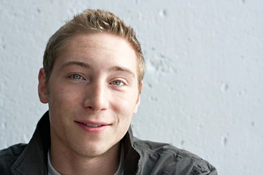 Close up portrait of a handsome smiling young man in his early twenties with dirty blonde hair.