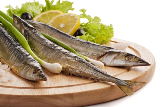 A composition with smoked saira fish (cololabis saira) on wooden plate isolated on white. Closeup