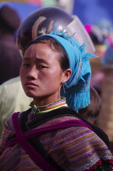 Woman Hmong flowered market of Lai Chau. Like all mothers, she is not separated from her baby she is carrying in the back.