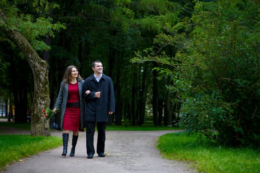 Two young lovers walking together in park