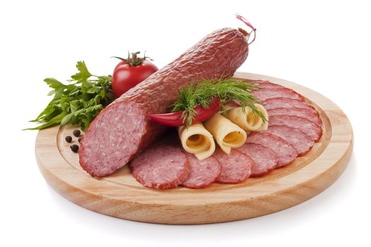 Sliced sausage with vegetables on a wooden plate isolated