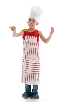 A young six year old chef in apron and chef hat holding a kitchen utensil.  White background.