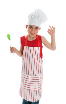 A young smiling child chef in apron and chef hat with an okay hand sign.  White background.