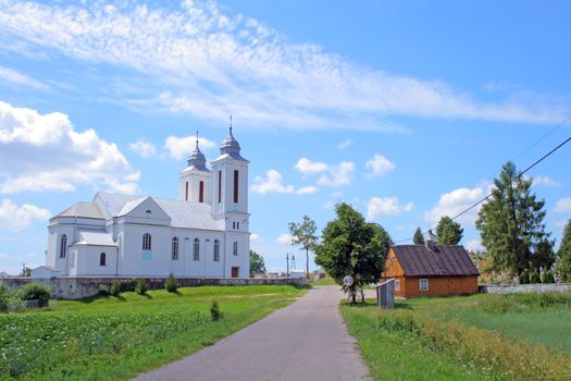 Road in the village with church and wooden house