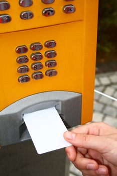 Woman putting the white card into the public telephone