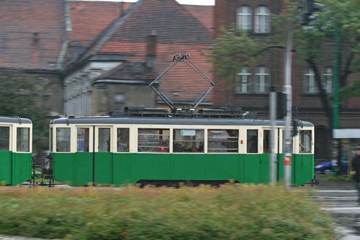 Old tram running through the city center with a motion-blurred background