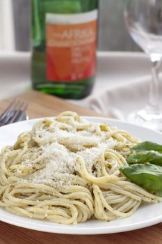 Pesto spaghetti dinner with white wine, vertical image orientation