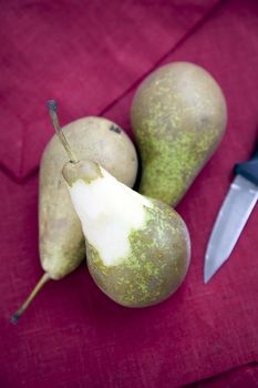Still life: pears on red linen with paring knife.