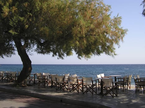 Landscape at early morning with traditional greek restaurant at coast line and sky line in background.