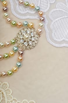 Beautiful pearl necklace with brooch on lace background