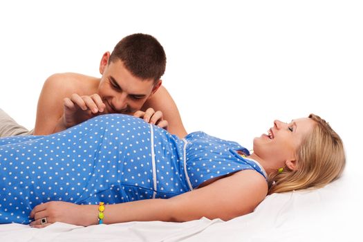 Pregnant woman with her husband playing with a belly. Studio shoot on white.