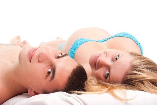 Pregnant woman with her husband laying on white and smiling. Studio shoot on white.