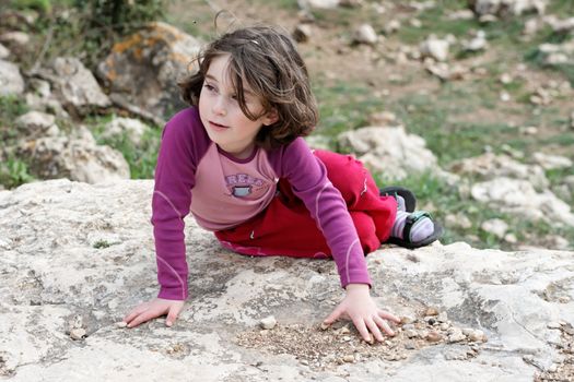 Little girl lies on the rock